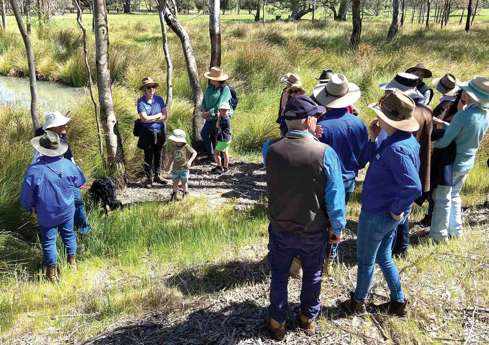 Angelina Seigrist (front left) and Amber Croft (front right) explain the benefits of revegetation around a fenced dam.